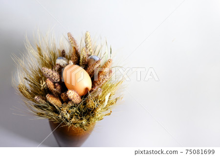 Easter eggs in a nest of dried flowers. On a gray background. Easter eggs in a nest of dried flowers. On a gray background. 75081699