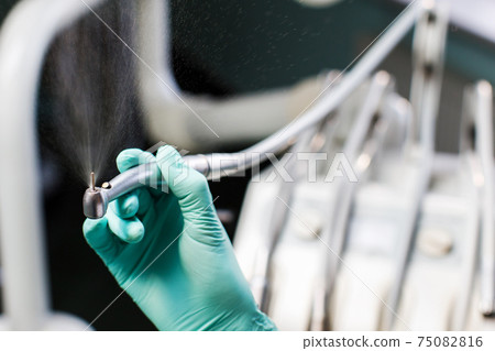 Dental tools in your hand. Professional woman dentist doctor working. Close up of dentist hand drilling the teeth and spraying the water 75082816