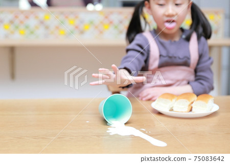 Daughter spilling milk during a meal 75083642
