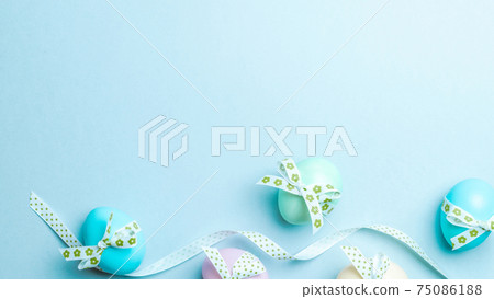 Easter luxury. Colorful egg with tape ribbon on pastel blue background in Happy Easter decoration. Flat lay, top view. 75086188