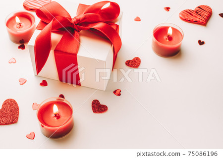 Valentine day composition: red love hearts, romantic gift box, candle on white background. February romance present card. Valentine day composition: red love hearts, romantic gift box, candle on white background. February romance present card. 75086196
