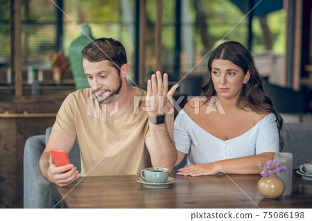 Bored woman and busy man with smartphone Bored woman and busy man with smartphone 75086198