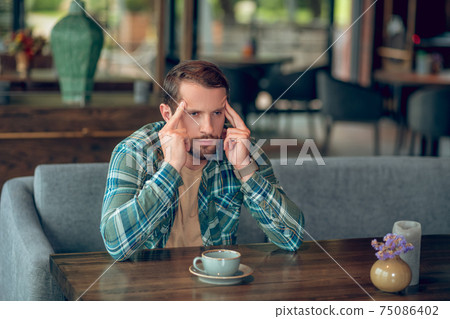 Sad man with cup of coffee in cafe Sad man with cup of coffee in cafe 75086402