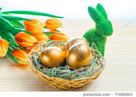Easter Golden eggs in basket with spring tulips, white feathers on wooden background in Happy Easter decoration. Spring holiday concept. 75086801
