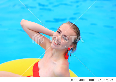 A beautiful young girl lies on an inflatable mattress in the summer water park. A beautiful young girl lies on an inflatable mattress in the summer water park. 75087096