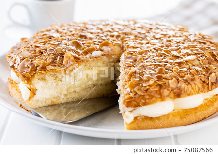 Sliced sweet almond cake on plate. Pie with cream and almonds. 75087566