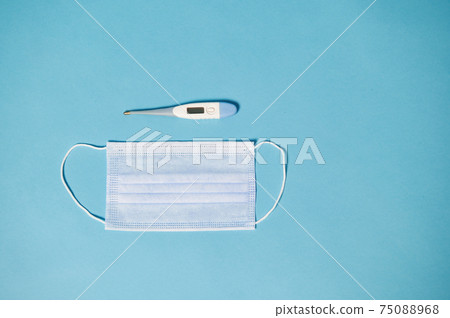 High angle view of protective medical mask and thermometer on blue background with copy space 75088968