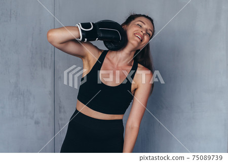 Young woman boxer jokingly beats herself. Young woman boxer jokingly beats herself. 75089739