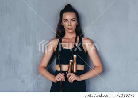 Sporty woman with a jump rope looks at the camera 75089773