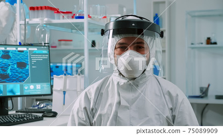 Overworked chemist sitting in equipped lab wearing coverall Overworked chemist sitting in equipped lab wearing coverall 75089909
