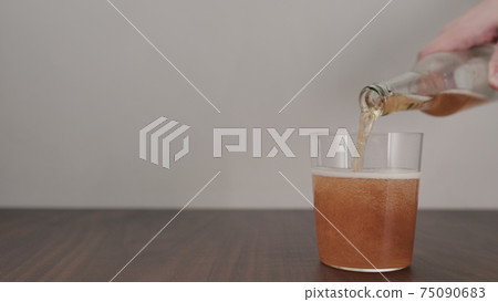 Slow motion pour orange drink in tumbler glass on walnut table with copy space 75090683