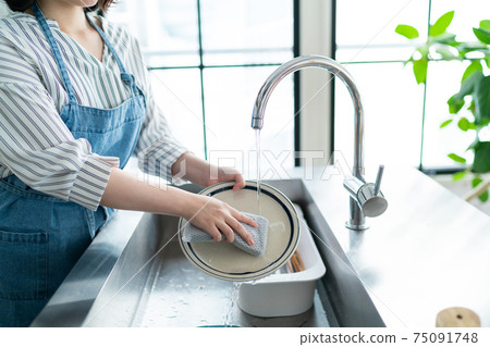 年輕的家庭主婦在廚房里站立 75091748