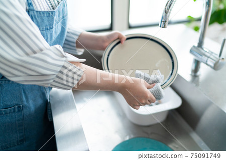 年輕的家庭主婦在廚房里站立 75091749