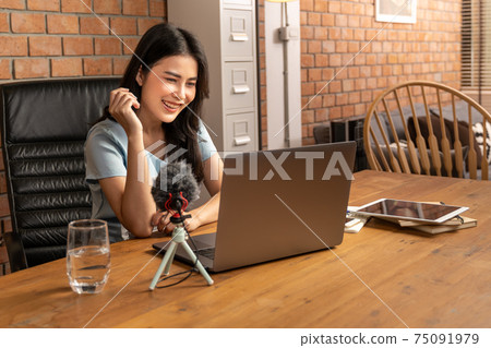 Happy young attractive woman working or learning online through her laptop computer at home in her living room 75091979