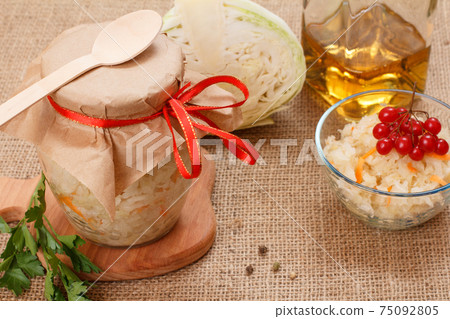 Fermented cabbage with herbs and spices in glass bowl and jar on the sackcloth Fermented cabbage with herbs and spices in glass bowl and jar on the sackcloth 75092805