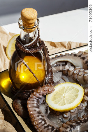 Olive oil with raw octopus on a plate with lemons ready for preparing Olive oil with raw octopus on a plate with lemons ready for preparing 75095366