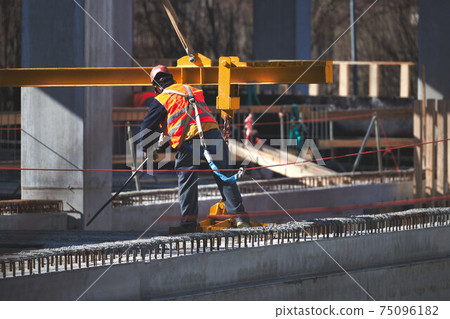 Construction site worker with safety harness hook Construction site worker with safety harness hook 75096182