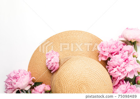 Summer holiday concept, straw braided hat, pink peony flowers on white background, top view Summer holiday concept, straw braided hat, pink peony flowers on white background, top view 75098489