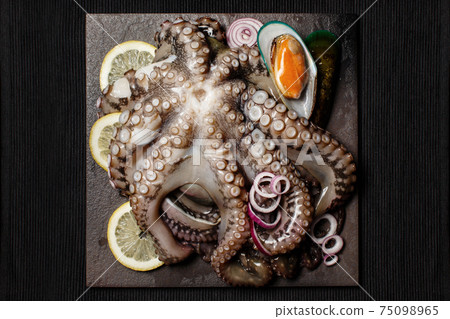 Seafood, whole raw big octopus on a stone dish served with mussels, lemon and red onion Seafood, whole raw big octopus on a stone dish served with mussels, lemon and red onion 75098965