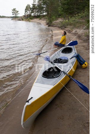 Woman sitting on the beach relaxing after kayaking 75099252