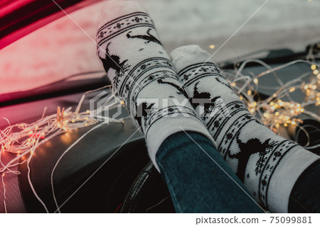 Woman legs with socks and winter car. Christmas socks. Garland defocused lights Woman legs with socks and winter car. Christmas socks. Garland defocused lights 75099881