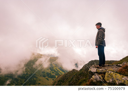 One tourist on the background of the Carpathian mountains, relaxation and enjoyment of nature and solitude. 75100979