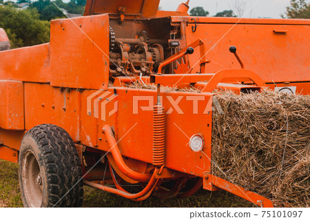 Old tractor in the field, forage harvesting for the winter, press and hay, pressing dry grass. 75101097