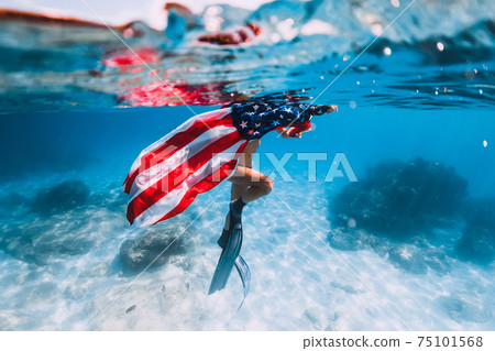 Freediver woman swim over sandy sea with United States flag. 75101568