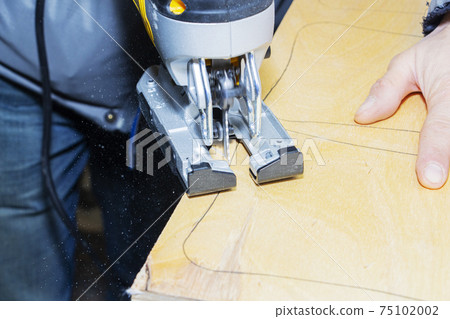 young man carpenter builder working with electric jigsaw and wood. young man carpenter builder working with electric jigsaw and wood. 75102002