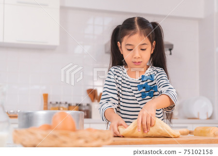 Asian girl having fun preparing home made pizza dough in home kitchen with copy space. Asian girl having fun preparing home made pizza dough in home kitchen with copy space. 75102158