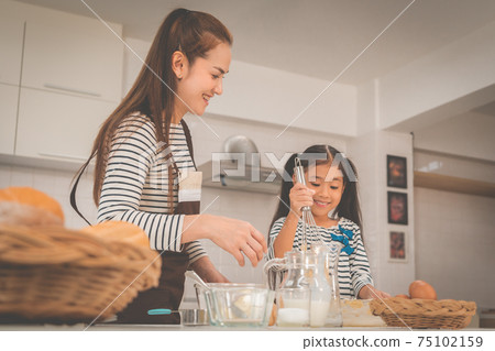 Mother and child is having fun preparing bakery in home kitchen for family activity concept. Mother and child is having fun preparing bakery in home kitchen for family activity concept. 75102159