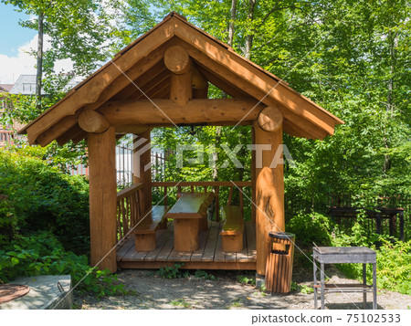 Beautiful summer house from a log of a large tree with barbecue for barbecue in forest Beautiful summer house from a log of a large tree with barbecue for barbecue in forest 75102533