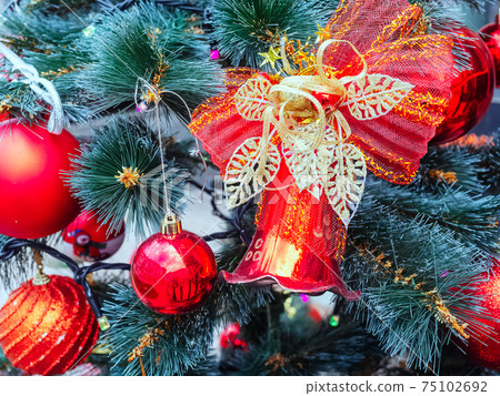 Red Christmas decorations hang on pine branches. Close-up photos 75102692