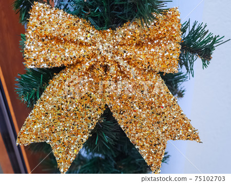 Shiny sequin bow hanging on an artificial spruce branch Shiny sequin bow hanging on an artificial spruce branch 75102703