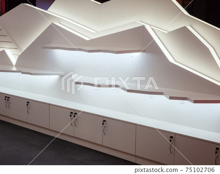 Decorative illuminated shelves on the wall in the form of mountains with white small cabinets underneath. Showcase for goods 75102706