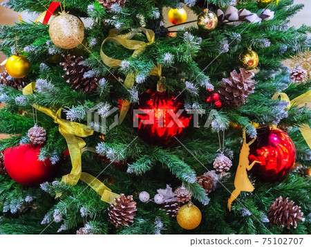 The Christmas tree is decorated with red and gold balls, ribbons and pine cones. Closeup photo The Christmas tree is decorated with red and gold balls, ribbons and pine cones. Closeup photo 75102707