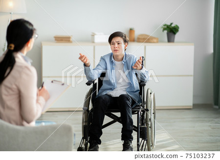 Professional psychological help for disabled teens. unhappy handicapped adolescent talking to psychotherapist at office Professional psychological help for disabled teens. unhappy handicapped adolescent talking to psychotherapist at office 75103237