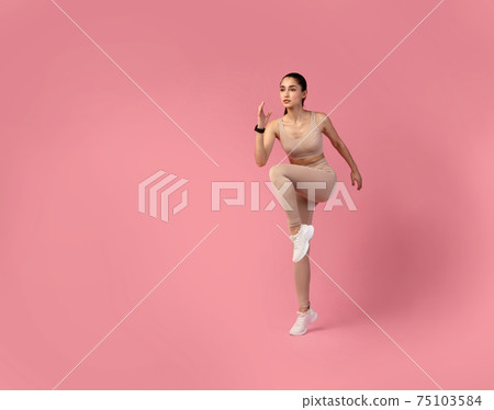 Young Woman Doing High Knees Exercise Isolated On Pink Background Young Woman Doing High Knees Exercise Isolated On Pink Background 75103584