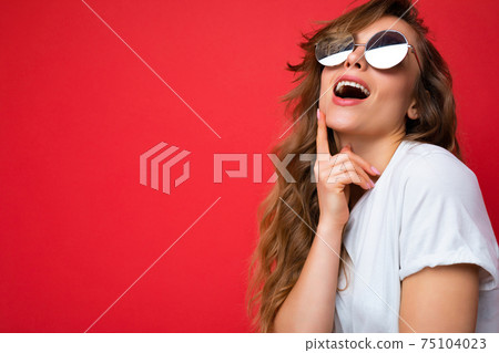 Shot of beautiful thinking young dark blonde curly woman isolated over red background wall wearing Shot of beautiful thinking young dark blonde curly woman isolated over red background wall wearing 75104023