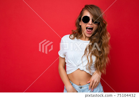 Photo shot of beautiful positive young blonde woman wearing casual clothes and stylish sunglasses 75104432