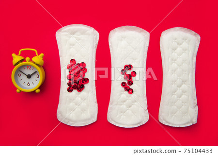 Menstrual pads with bright red glitter and alarm on red background. Woman periods cycle, menstruation frequency. Minimalist still life photography concept 75104433