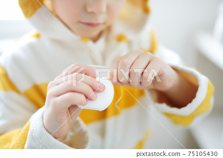 Preschooler boy cleaned teeth with dental floss and then is brushing his teeth with toothbrush 75105430