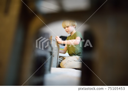 Little child is playing with toy prototype Medieval Castle. Little child is playing with toy prototype Medieval Castle. 75105453