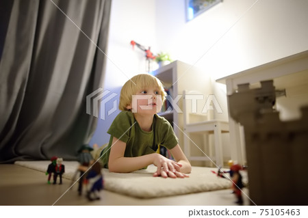 Little child is playing with toy prototype Medieval Castle. Little child is playing with toy prototype Medieval Castle. 75105463