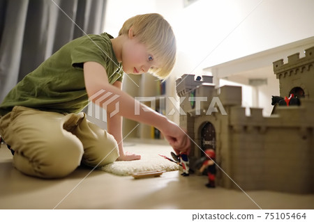 Little child is playing with toy prototype Medieval Castle. Little child is playing with toy prototype Medieval Castle. 75105464