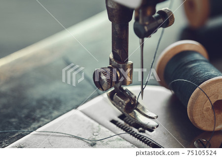Close up of sewing needle. Spool of thread on working part of antique sewing machine. Close up of sewing needle. Spool of thread on working part of antique sewing machine. 75105524