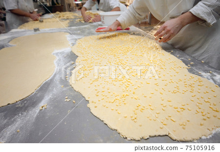 Manual cutting of dough for making cookies at the factory in the bakery Manual cutting of dough for making cookies at the factory in the bakery 75105916