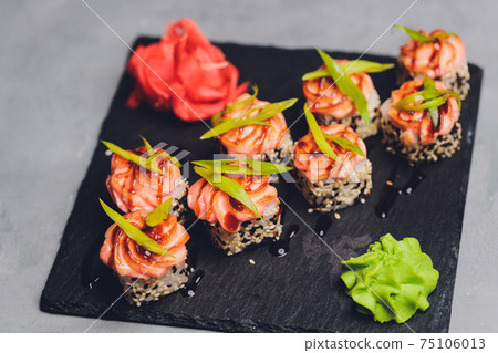 Maki Sushi Rolls with salmon on black stone on dark background. With ginger and wasabi. Sushi menu. Japanese food. Closeup of delicious japanese food with sushi roll. Horizontal photo. 75106013