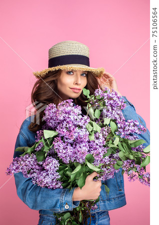 Happy smiling woman enjoying smell of bouquet lilac flowers over 75106564