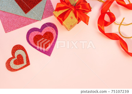 Packaging Valentine's Day or birthday presents. Valentine's Day gifts with a red paper heart on a pink background. Top view. 75107239
